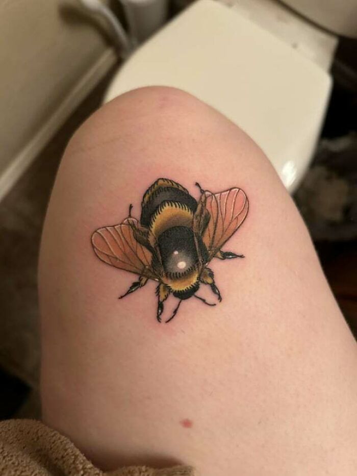 A bee tattoo on the knee, showcasing bold and intricate design details.