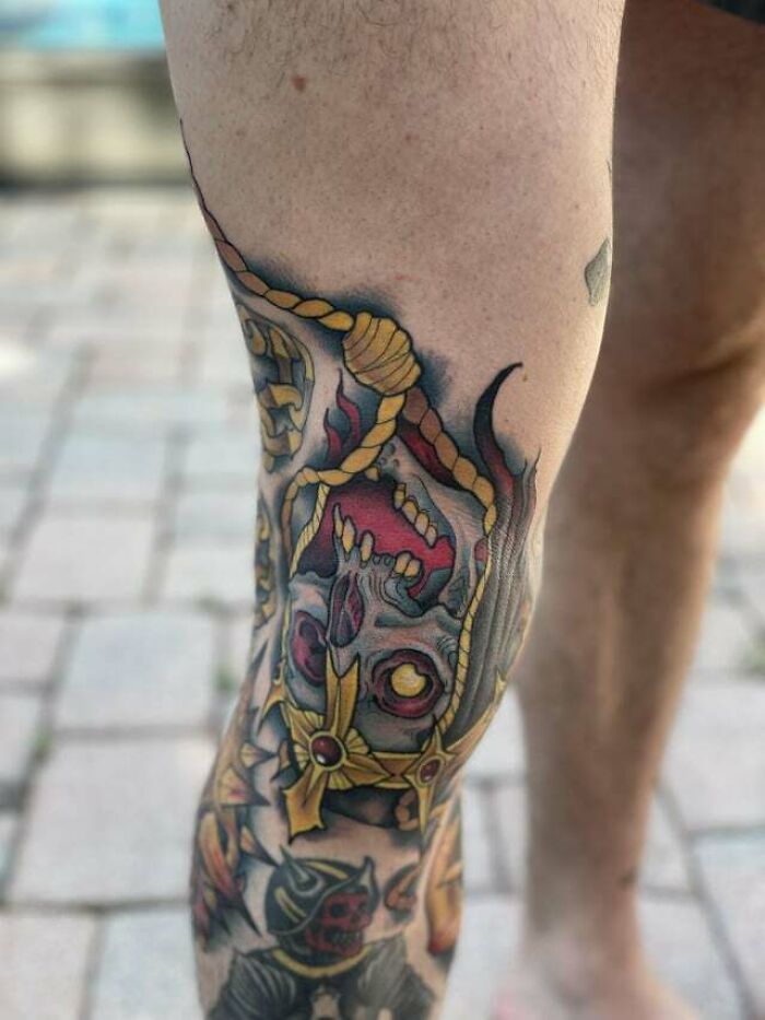 Colorful knee tattoo featuring a skull design with ropes and vibrant details.