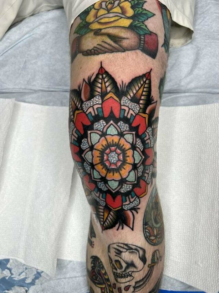 Knee tattoo with a colorful mandala design, featuring bold geometric patterns and intricate details.