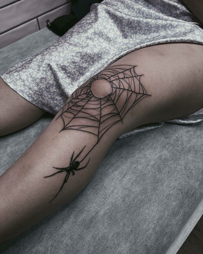 Spider web knee tattoo design on a person's leg.