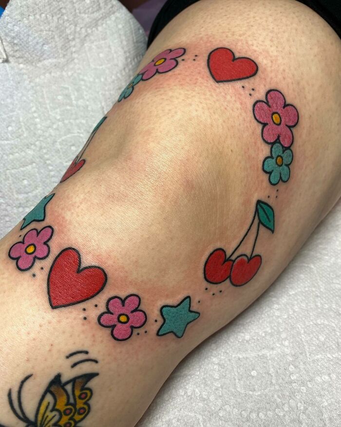 Colourful flowers and heart around knee tattoo 