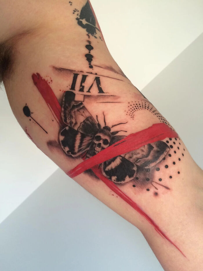 Trash Polka tattoo design featuring a moth, red brush strokes, and black abstract elements on an arm.