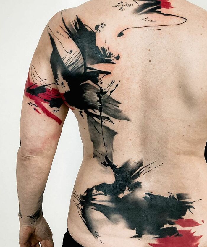 Back view of a stunning Trash Polka tattoo featuring bold black and red abstract designs.