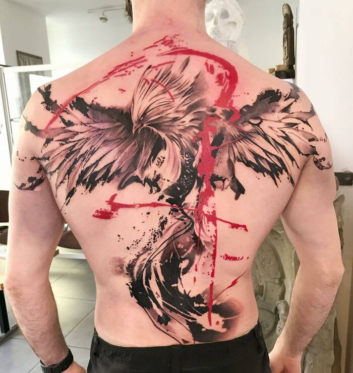 Man with a full back Trash Polka tattoo featuring bold red and black abstract design.