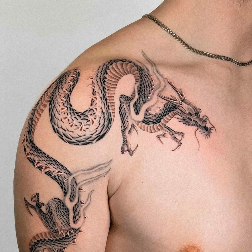 detailed shoulder tattoo of a dragon with large claws in black ink