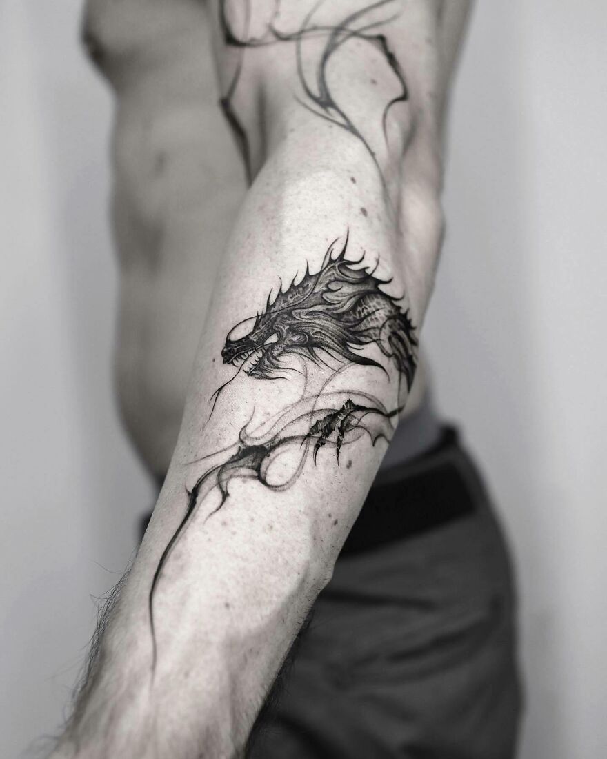 black and white image of a dragon tattoo on forearm