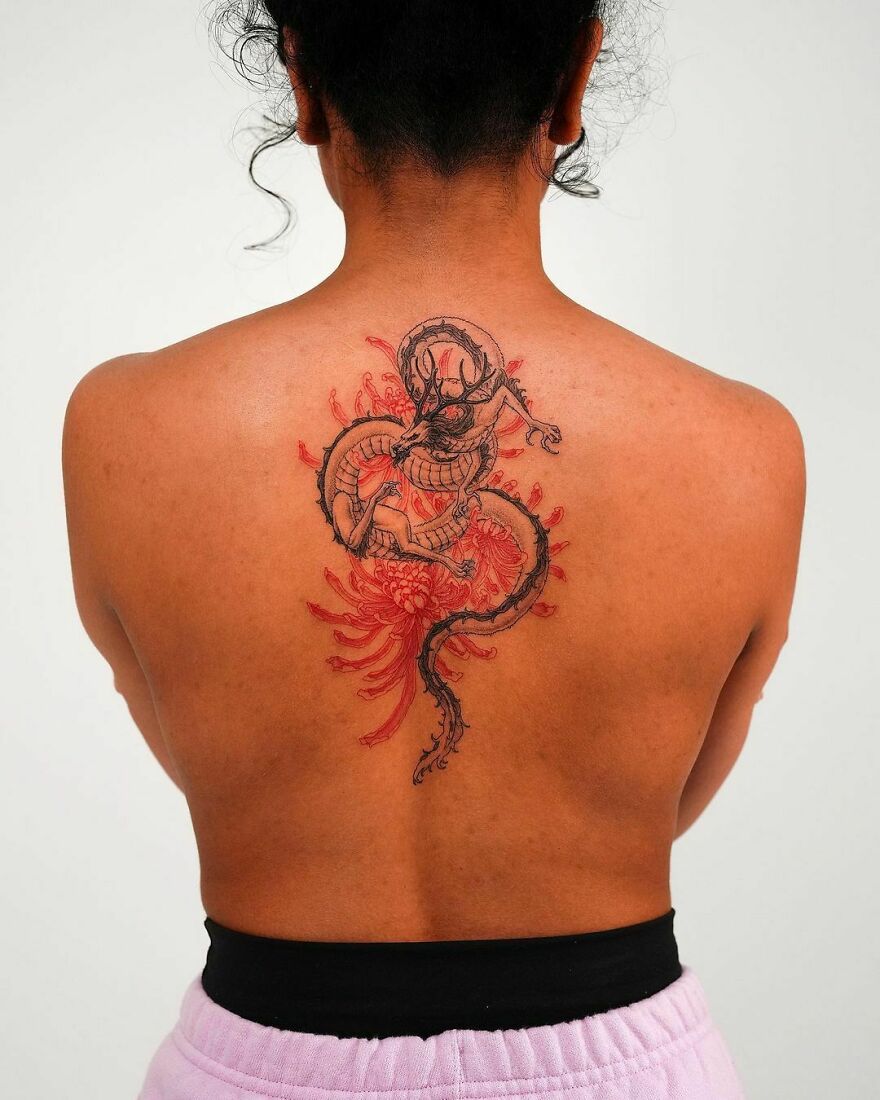 a woman with a dragon tattoo on her back with floral designs