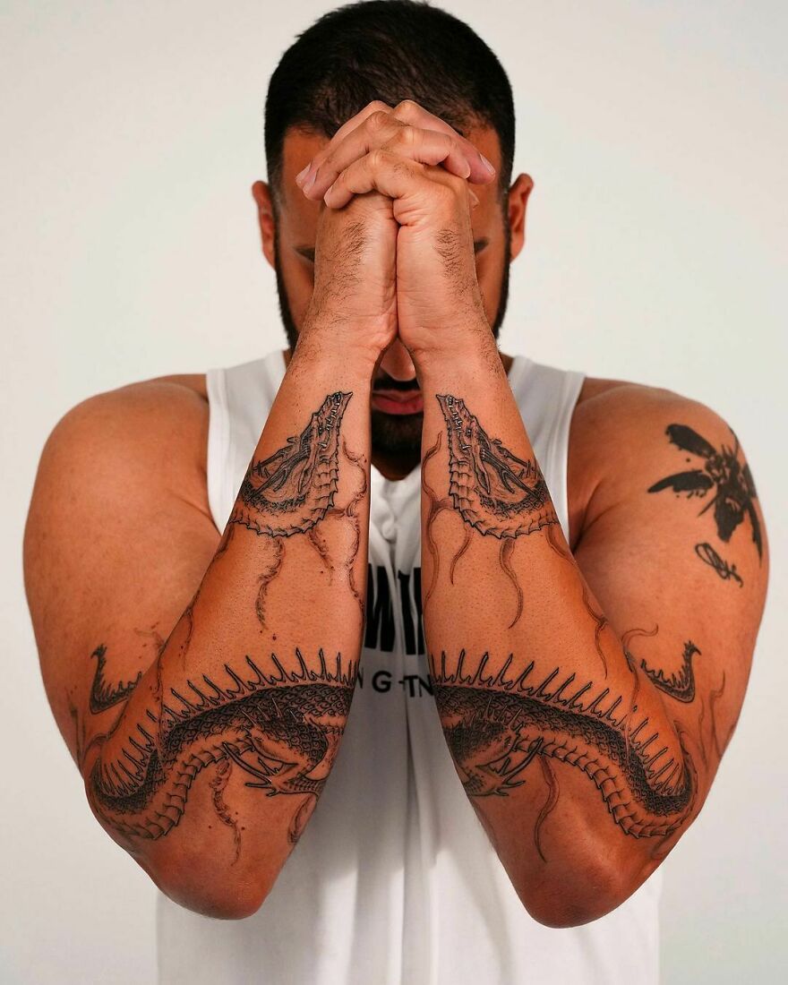 a man showing his dragon tattoos on both of his arms