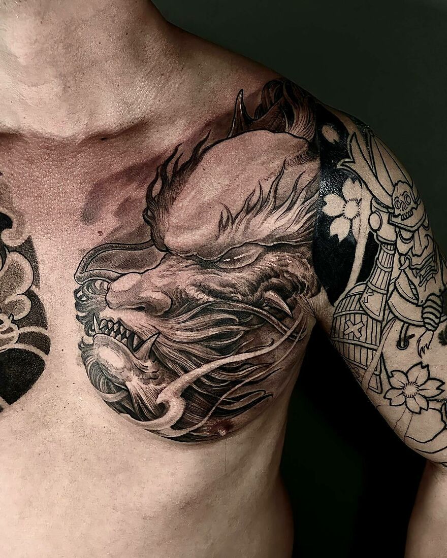 a tattoo of a dragon's face on upper chest 
