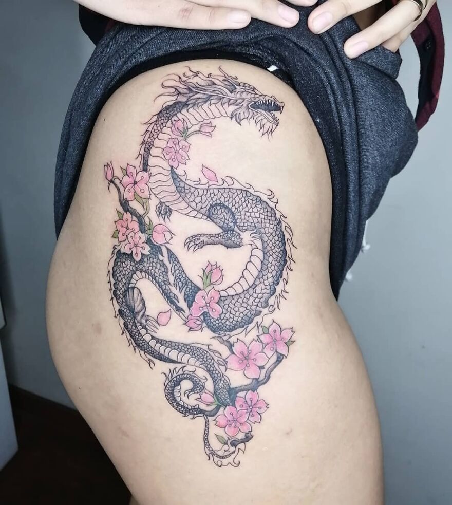 Thigh Tattoo Of A Black Ink Dragon With Pink Cherry Blossom Decorations