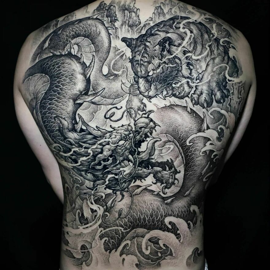 black ink back tattoo of a dragon fighting with a tiger