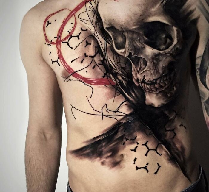 A striking trash polka tattoo with a skull and abstract elements, covering a man's chest.