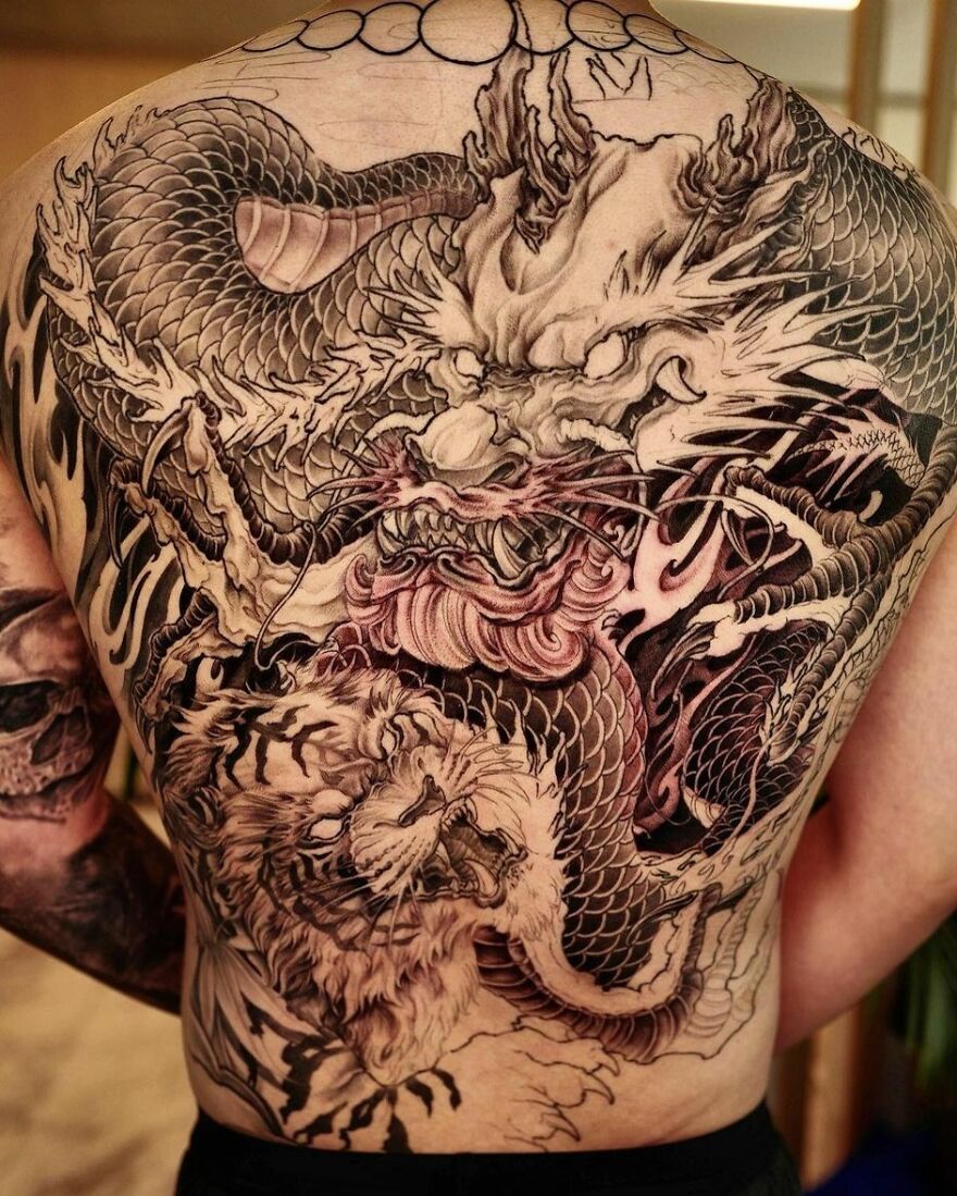 a dragon and tiger fighting tattoo design on the back