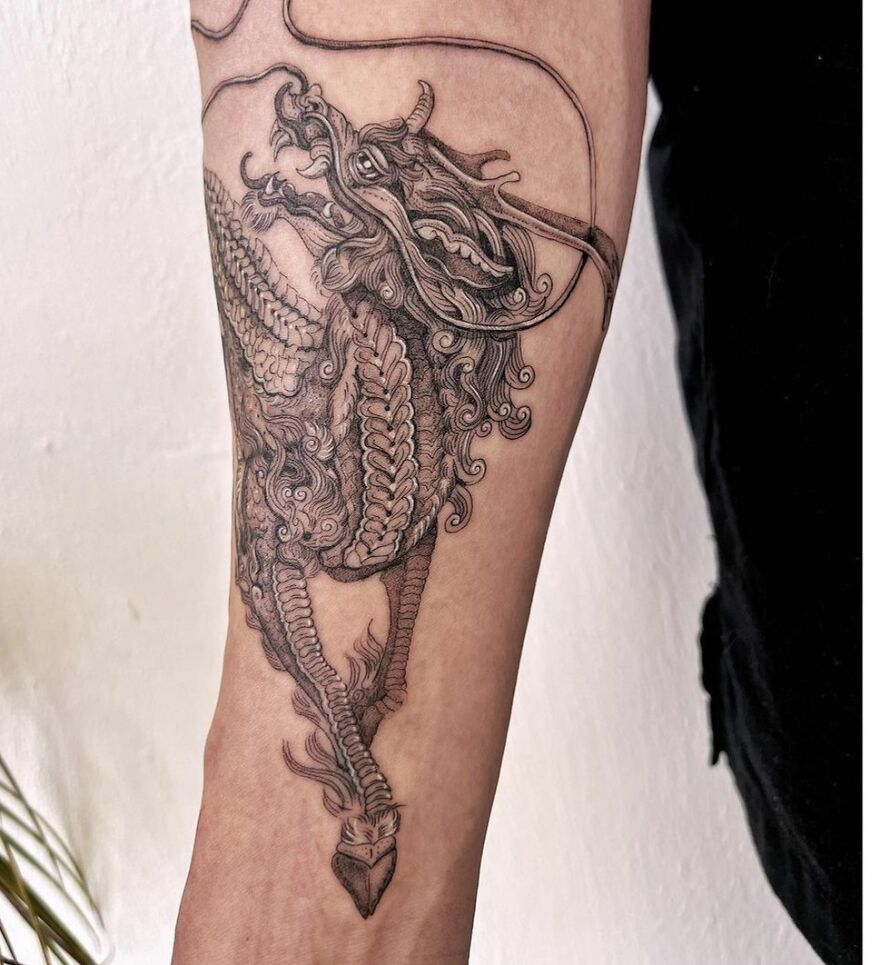 detailed tattoo of a dragon on forearm in black ink