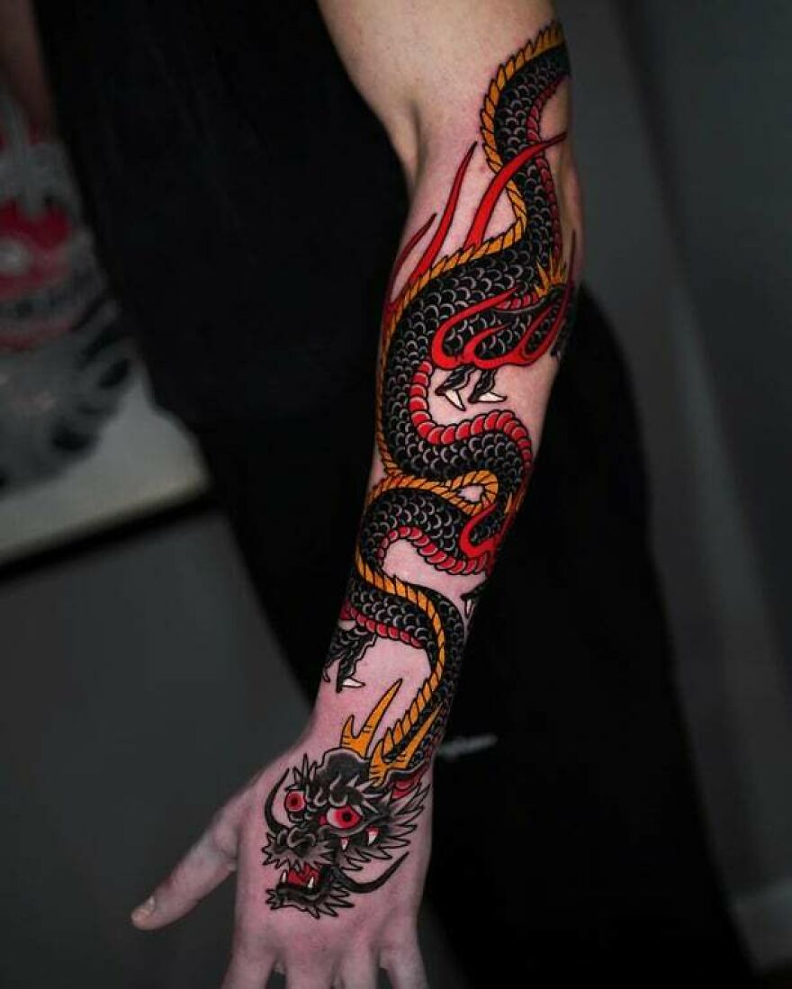 full sleeve tattoo of a black dragon with red and yellow scales