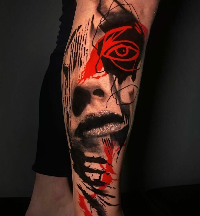 Trash Polka tattoo showcasing abstract face with red and black ink on an arm.