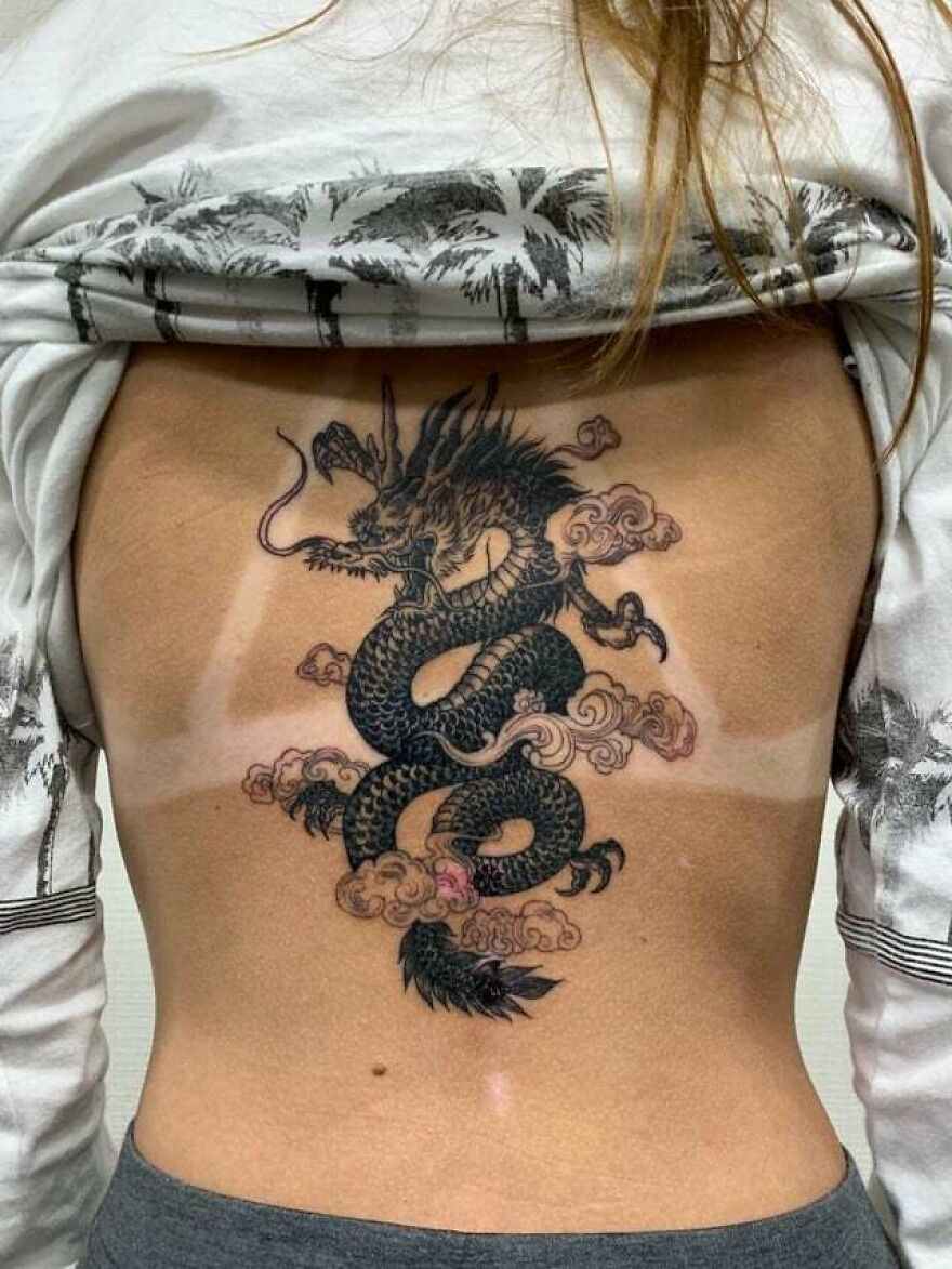 a flying dragon surrounded by clouds tattoo