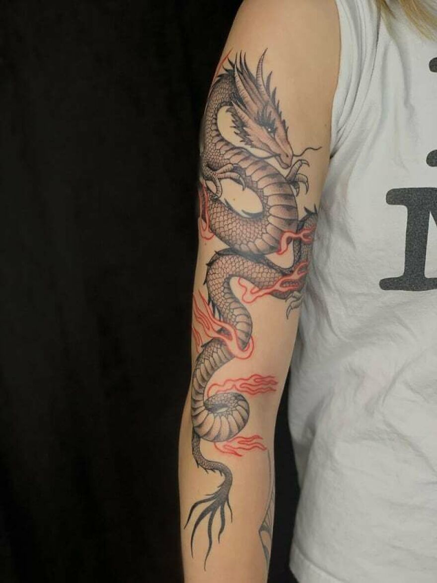 black ink dragon tattoo surrounded by red colored flames 