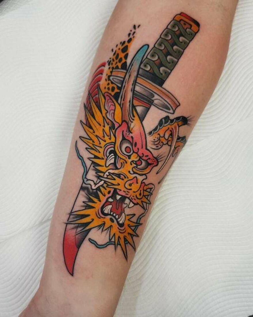 simple tattoo of a dragon head and a knife