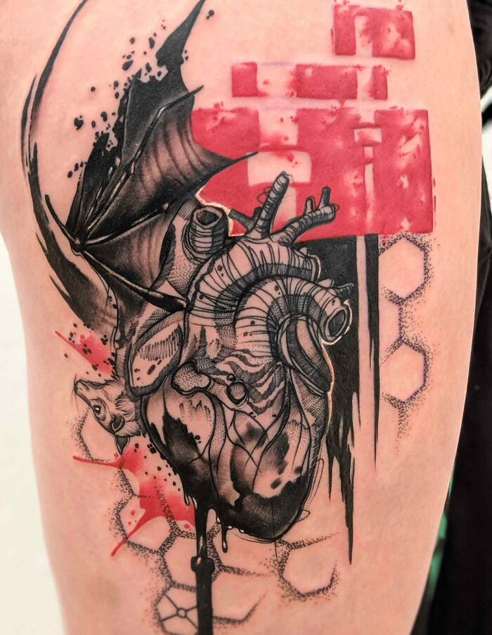 Trash Polka tattoo featuring a heart and bat wing design with red accents and abstract elements.