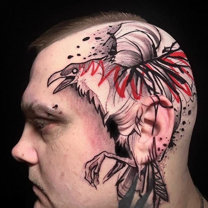 Side view of a head with a trash polka tattoo featuring a crow with red accents and abstract elements.