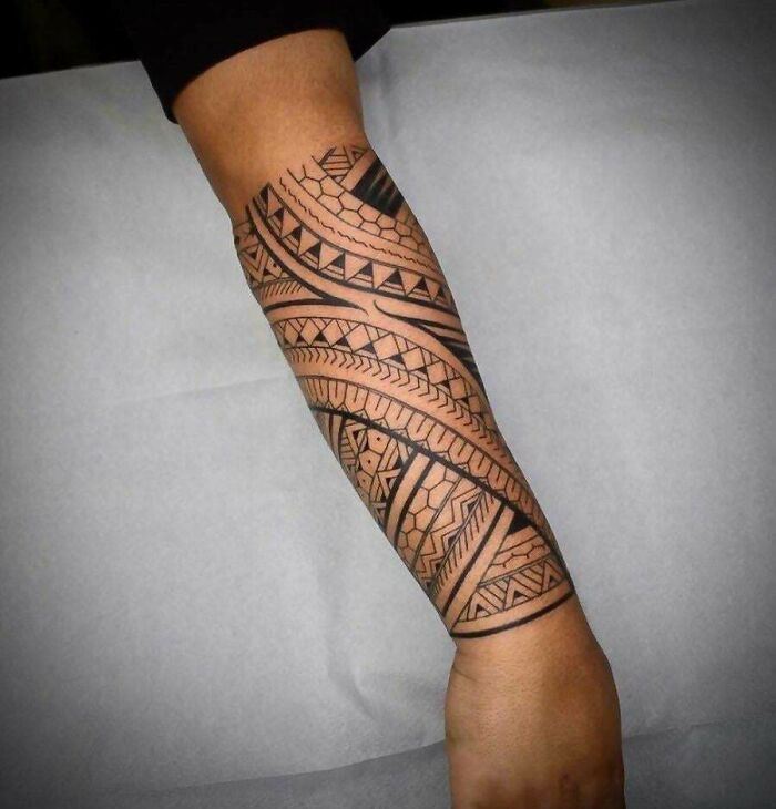 Arm adorned with a detailed tribal tattoo design showcasing intricate geometric patterns.