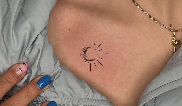 moon with rays under collarbone tattoo
