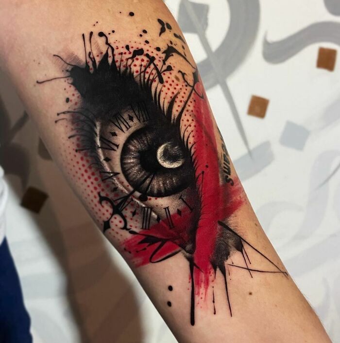 Trash Polka tattoo design featuring an eye with red and black abstract elements on forearm.