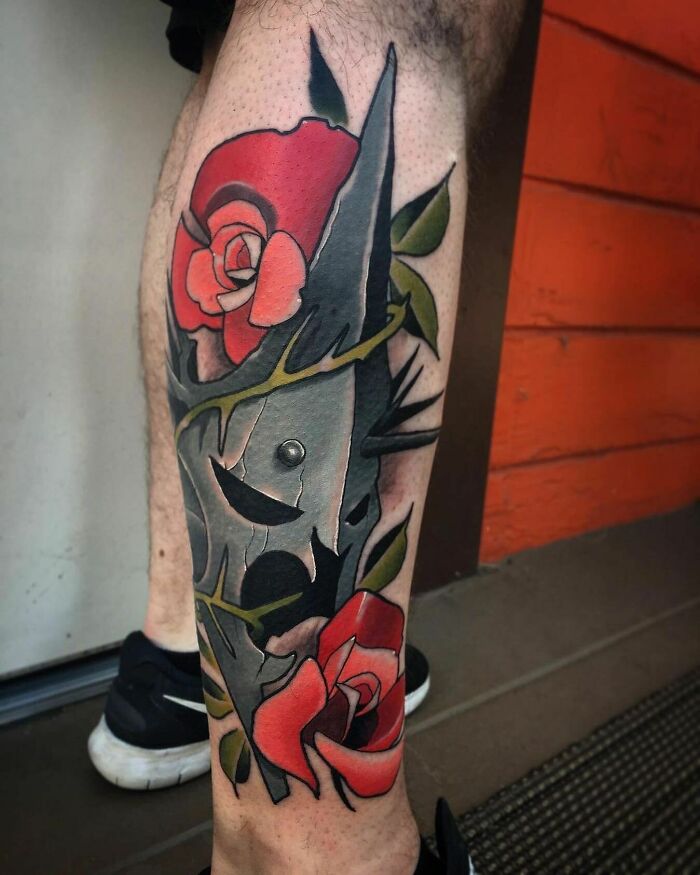 "Colorful Lord of the Rings tattoo with red roses and abstract elements on a leg."