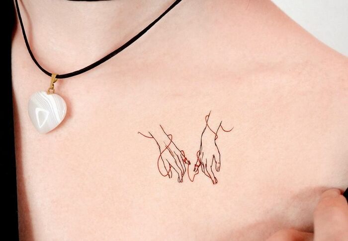 two hands with a red string Collarbone Tattoo