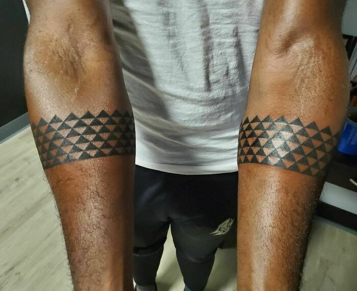 Arm tribal tattoos with geometric patterns in black ink.