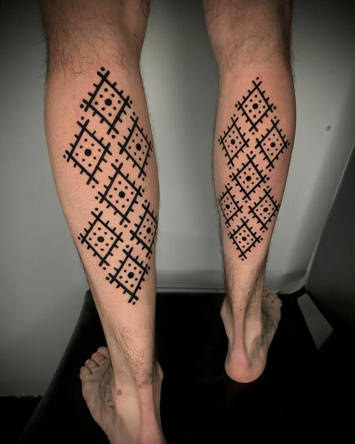 Legs with geometric tribal tattoo designs, featuring symmetrical diamond patterns in black ink.