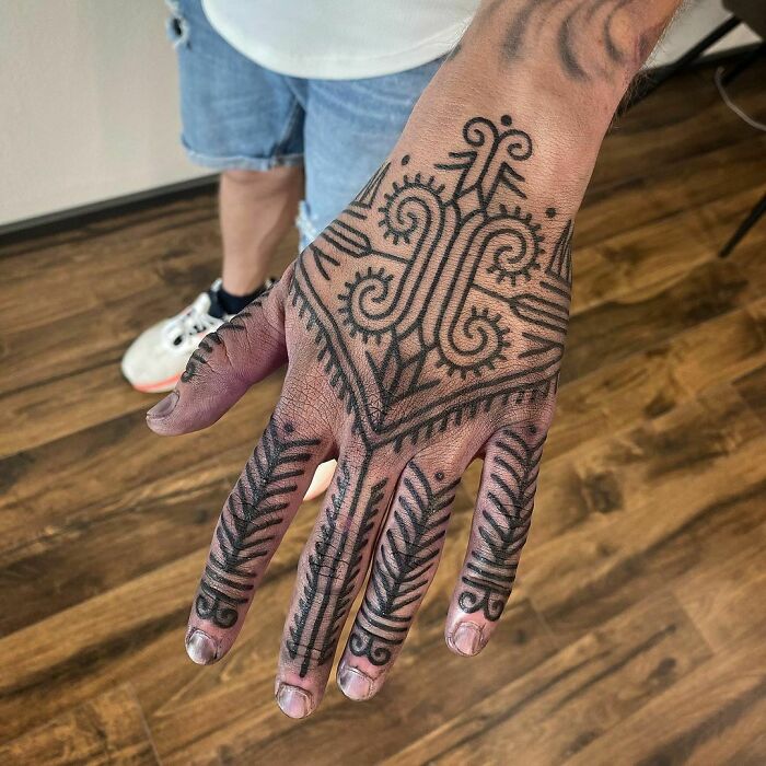Hand adorned with intricate tribal tattoo design showcasing artistic patterns.