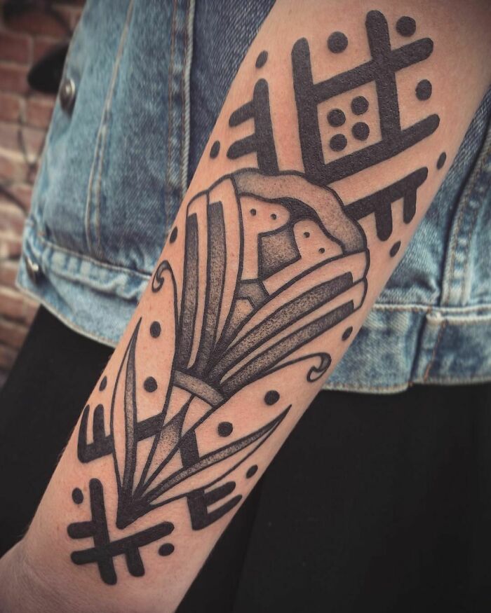 Close-up of a tribal tattoo on an arm featuring abstract geometric patterns and bold black ink designs.