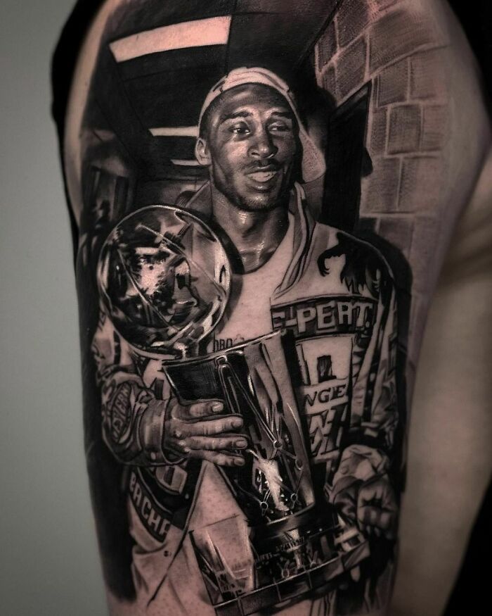 Black and gray pop culture tattoo of a smiling athlete holding a trophy on a person's arm.