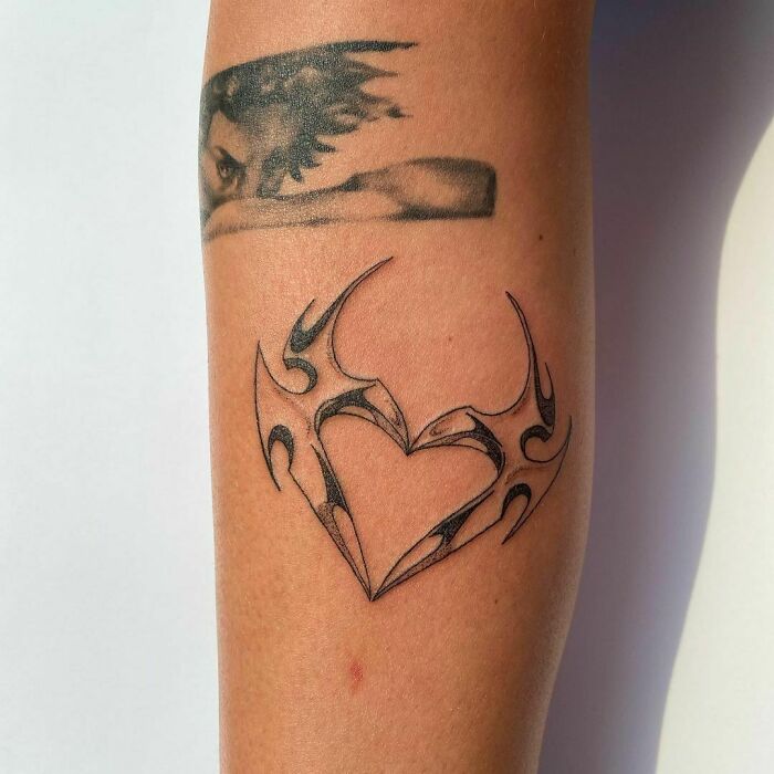 Tribal tattoo design on forearm, featuring sharp forms and bold lines that create a heart shape.