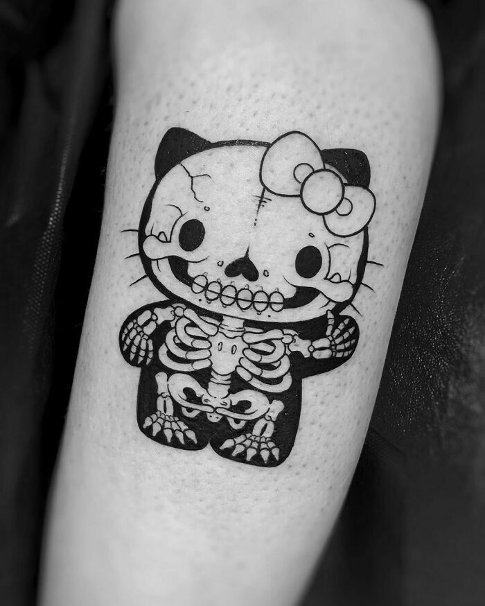 Skeleton-style Hello Kitty pop culture tattoo on forearm.
