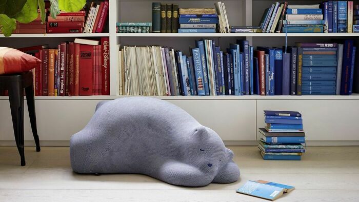 Chair - a sleeping polar bear toy next to a book shelf 