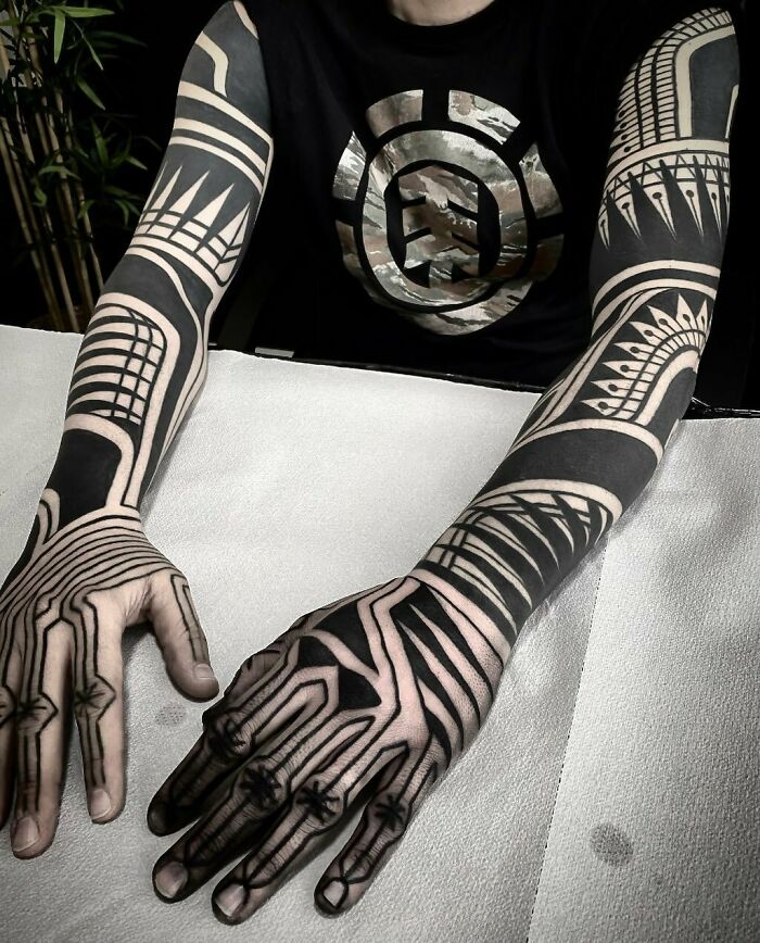 Tribal tattoo inspiration with bold geometric patterns covering both arms.