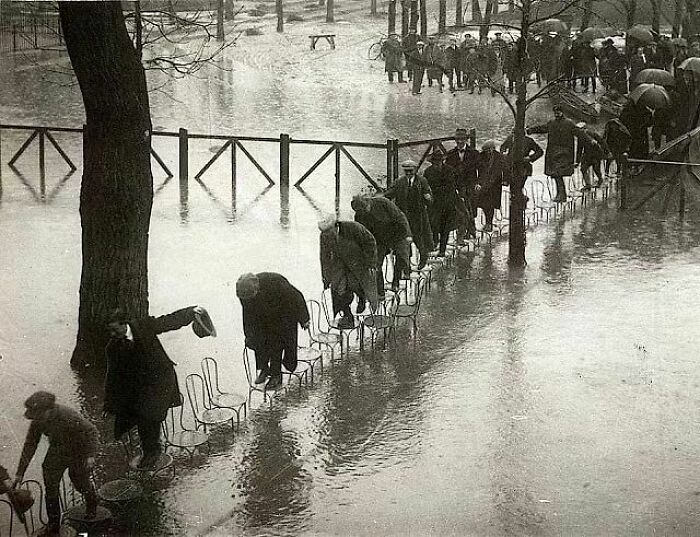 Parisians Walk Across A Row Of Chairs To Avoid Flood Waters In 1924. Photo By Henri Manuel