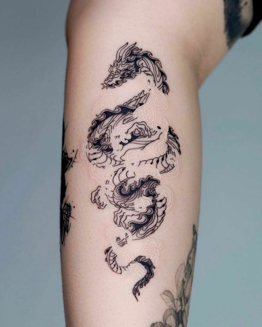 black and white ink forearm tattoo of a dragon