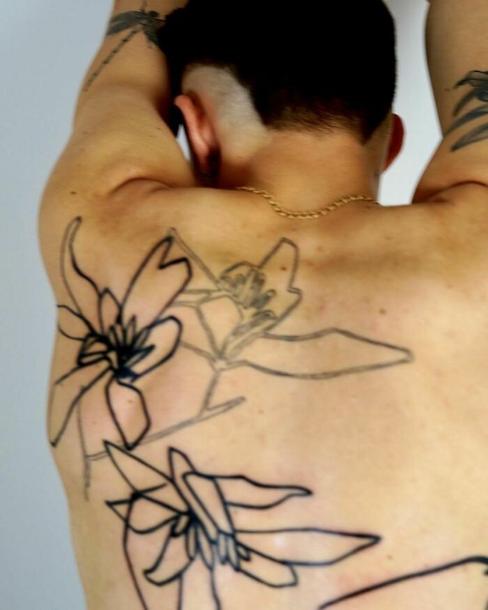 Tattoo artist's latest back piece featuring large floral outlines on a person's back. Tattoo artist's latest back piece featuring large floral outlines on a person's back.