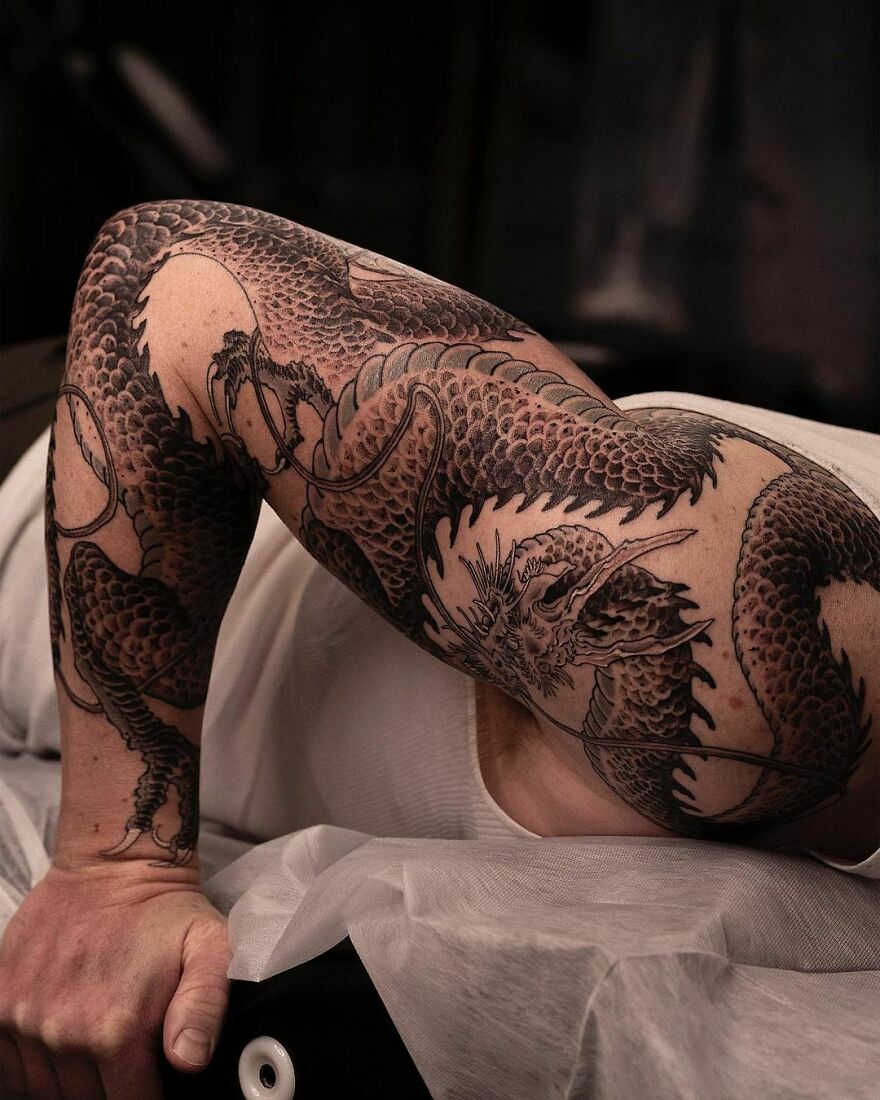 full length sleeve tattoo of a dragon in black ink
