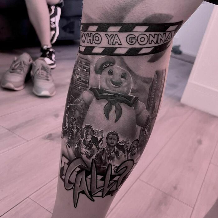 Pop culture tattoo featuring Ghostbusters theme with iconic characters and Stay Puft Marshmallow Man on a person's leg.