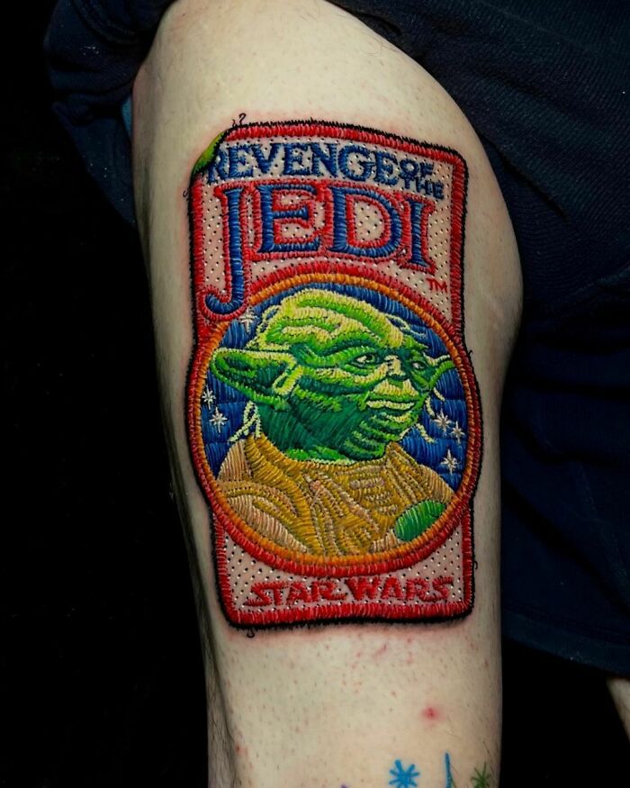 Pop culture tattoo of Yoda with "Revenge of the Jedi" design on a person's arm.