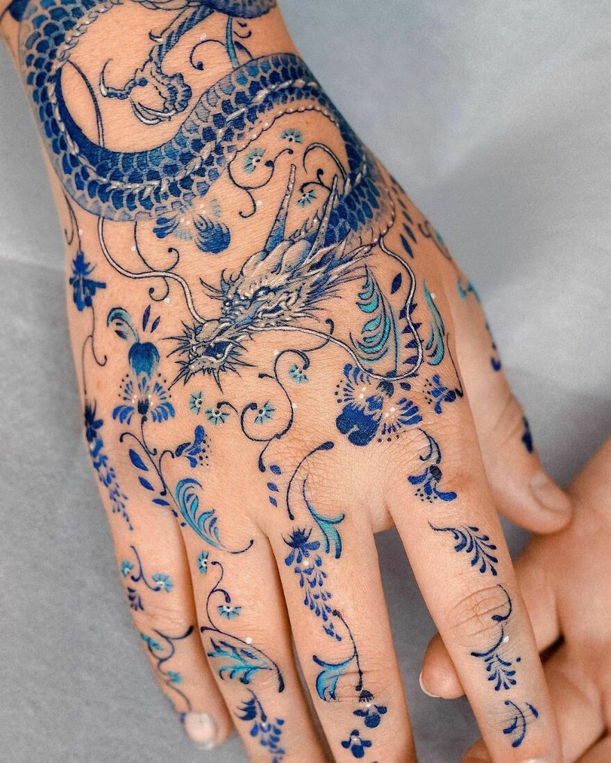 Blue Ink Tattoo Of A Dragon with Floral decorations