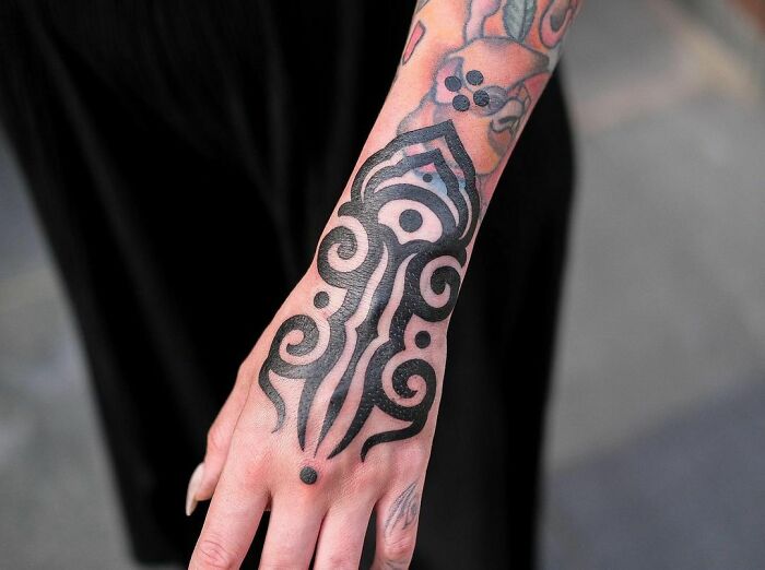 Close-up of a forearm with an intricate tribal tattoo design in black ink.