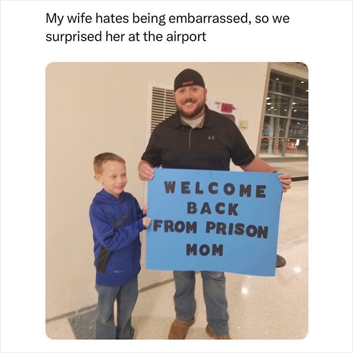 Father and son humorously welcome mom at airport with a funny sign, shared by the “Meme Lord” Instagram account.