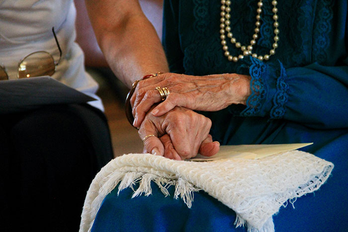 Grandparents holding hands gently, symbolizing loving connection and sharing wise, funny, and naughty advice together.
