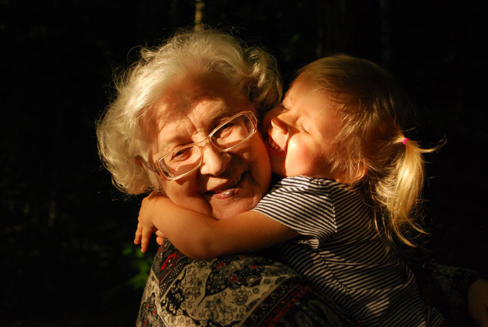 Grandma smiling and hugging a child outdoors, capturing warm moments of wise and funny advice from grandparents.